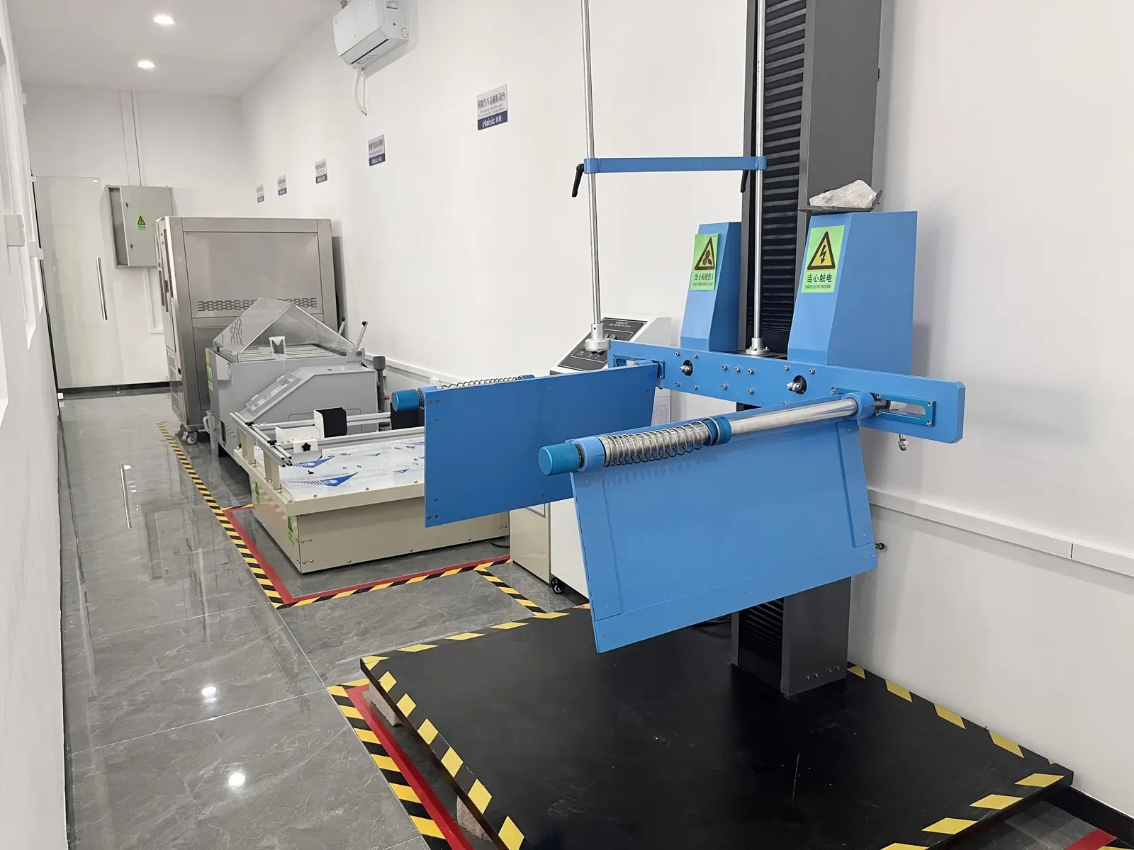 The test lab: a drop-test rig beside a simulated vehicle-transport vibration table and a climate chamber